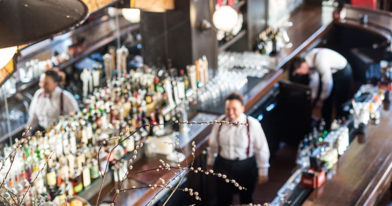 Bartender smiling with bar and other bartender in background